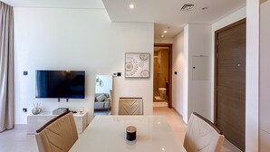 Een moderne woonkamer met een flatscreen televisie, een eettafel en een bank.