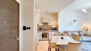 Een moderne keuken met inbouwapparatuur, een eethoek met tafel en stoelen, en een zithoek met een bank en decoratieve muurkunst.