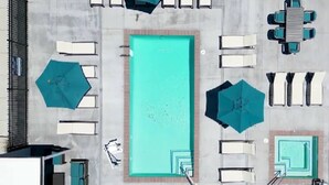 Ein rechteckiger Pool auf dem Dach, umgeben von Liegestühlen und Sonnenschirmen.