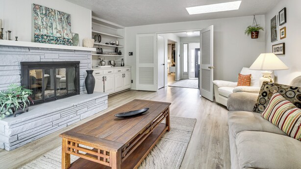 A living room with a fireplace, a sofa, a coffee table, and a kitchen area in the background. - Walk to UNM! Quiet Extended Escape w/ Patio (Albuquerque)