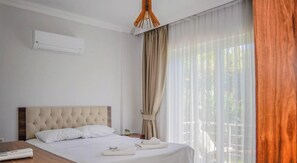 A hotel room with a bed, a bedside table, an air conditioning unit, and a window with curtains. - Fethiye Göcek Villa BegonVilla (Fethiye)