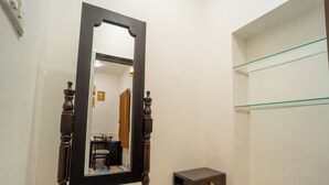 A bathroom with a wooden-framed mirror, a small wooden side table, and a glass shelf unit. - JAWAI INTO THE WILD (Bali)