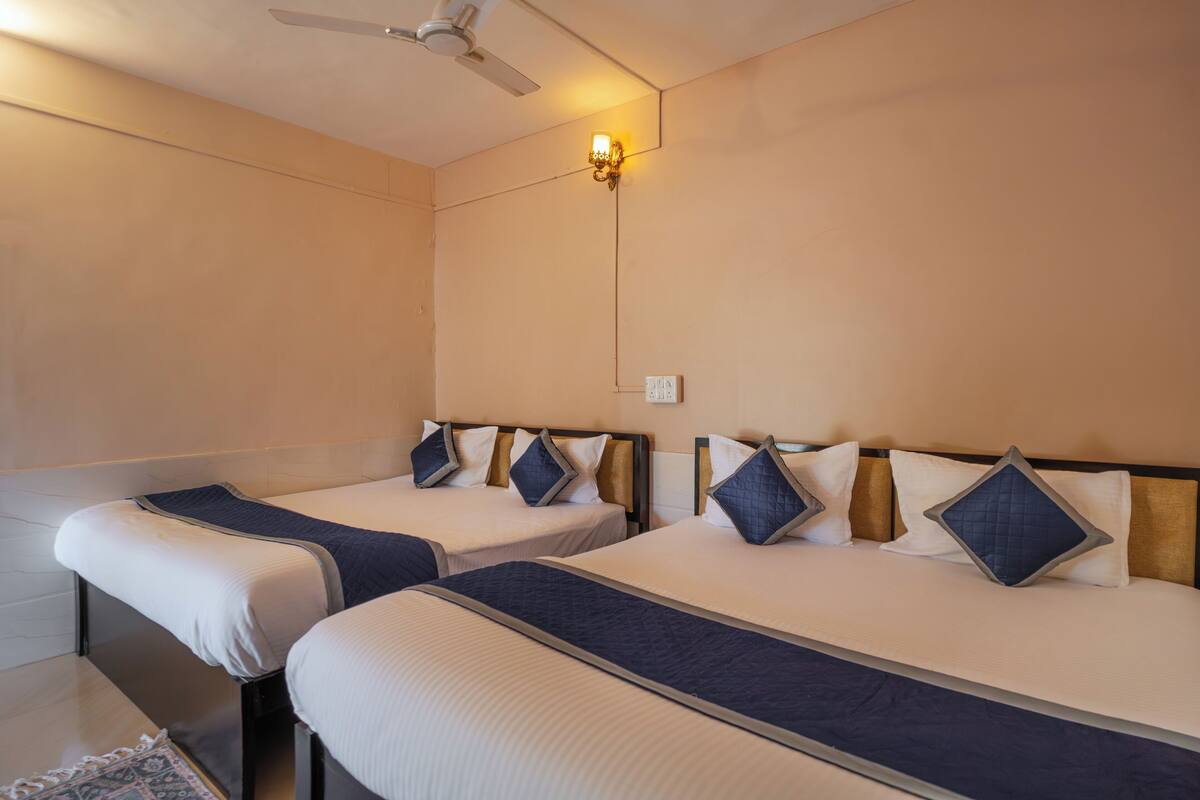 A hotel room with two beds, a ceiling fan, and a wall-mounted light fixture.