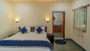 A bedroom with a bed, bedside tables, a mirror, and a bathroom door. - JAWAI INTO THE WILD (Bali)
