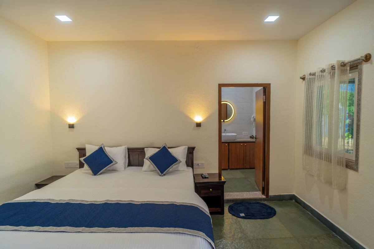 A bedroom with a bed, bedside tables, a mirror, and a bathroom door.