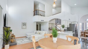Tilava olohuone, jossa on ruokapöytä, sohvia ja taustalla keittiö.