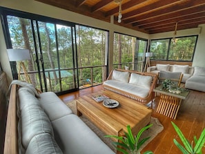 Un amplio salón con ventanas grandes, techo de madera y un conjunto de sofás.