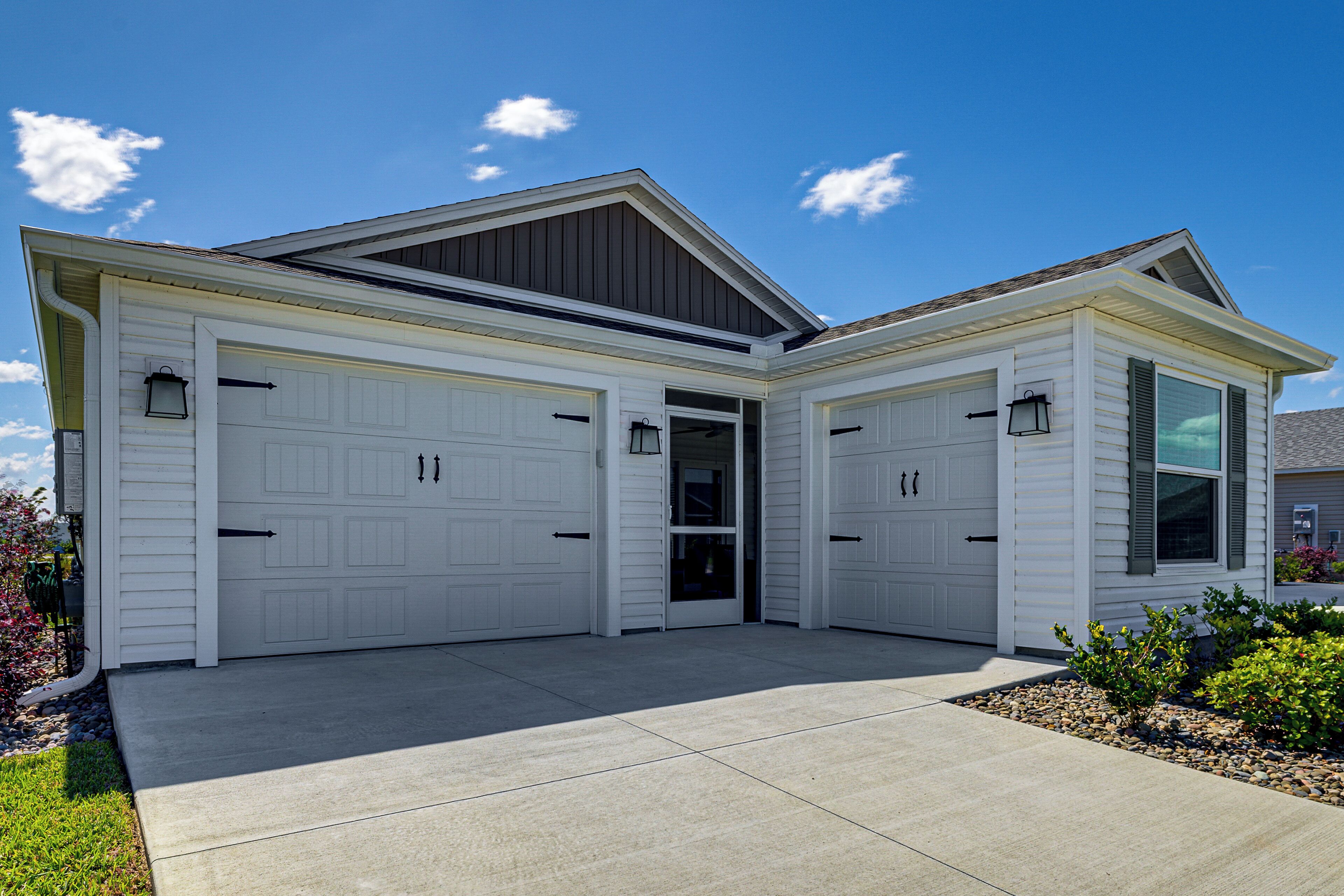 A two-story house with a garage, a front door, and a small garden area.