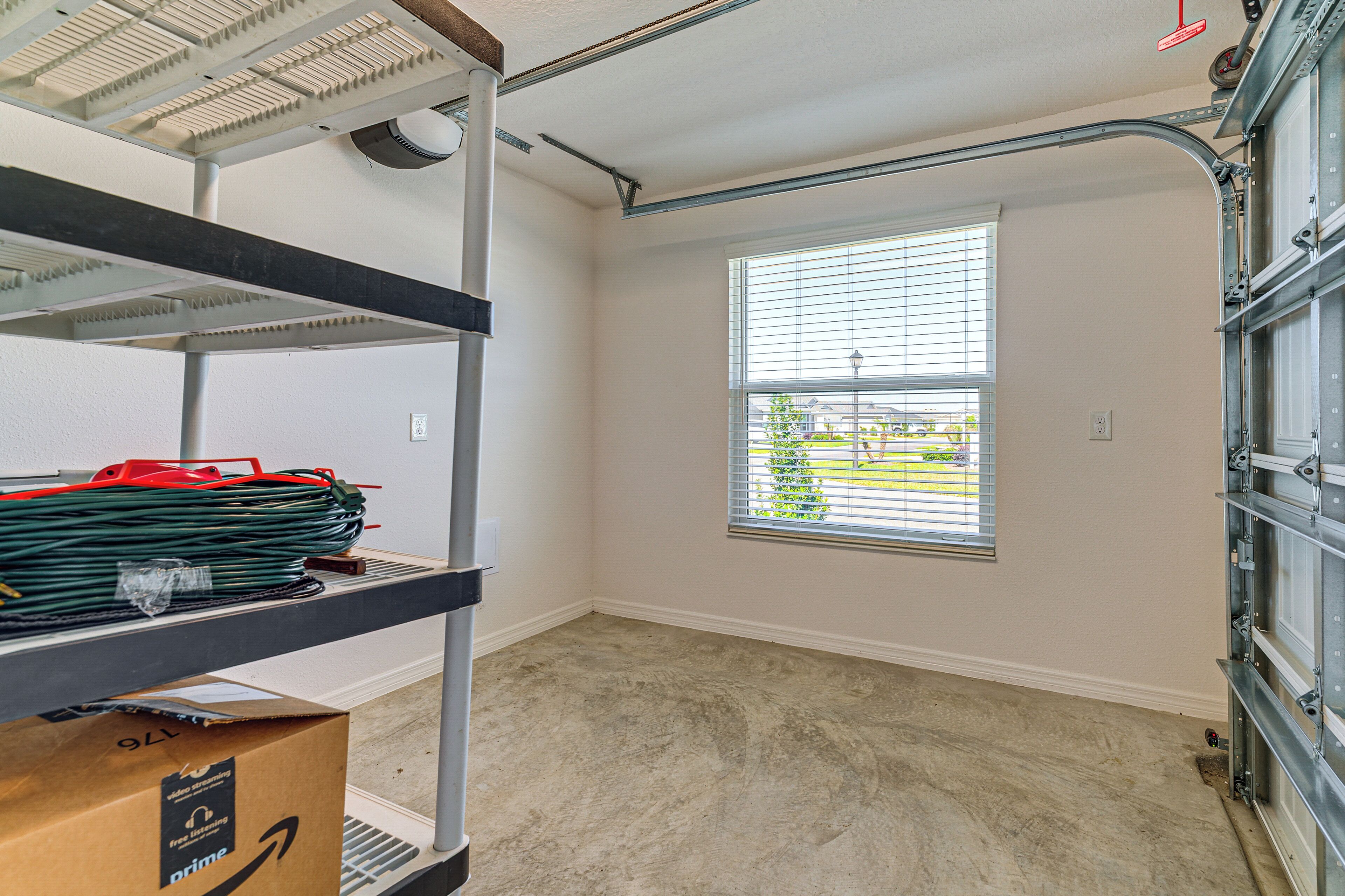 A room with a window, a metal shelf with items, and a garage door.