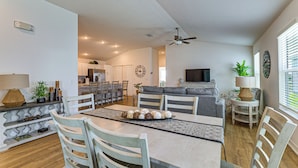 Un vaste espace de vie comprenant une table à manger, des chaises, un canapé et un téléviseur.