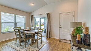 Un espace repas comprenant une table, des chaises, un tapis et une porte.