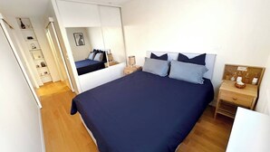 Ein Schlafzimmer mit einem Bett, Nachttischen, einem Kleiderschrank und einem Spiegel.