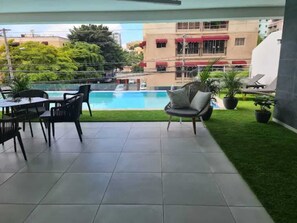 Un balcon avec une piscine, un espace salon extérieur et une vue sur les bâtiments.