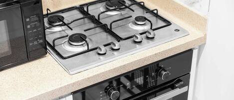 A kitchen with a gas stove, oven, and microwave.