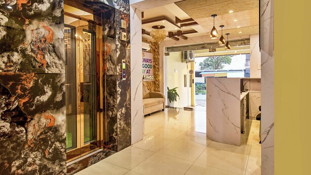 Un vestíbulo de hotel moderno con paredes de mármol, un mostrador de recepción, un sofá y una araña.