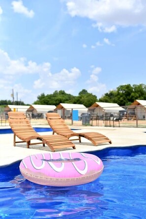 A swimming pool with lounge chairs and a pink inflatable ring.