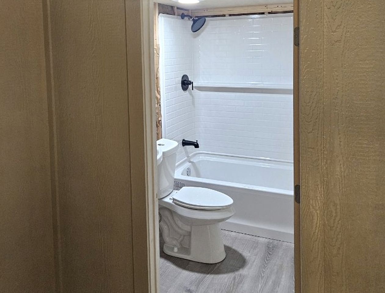 Un baño con inodoro, bañera y paredes de azulejos blancos.