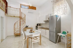 A kitchen with a dining table, chairs, a refrigerator, a stove, and a staircase.