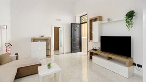 Una sala de estar moderna con un sofá, televisión y una pequeña mesa con una planta.
