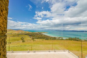 A coastal landscape with a clear sky, a body of water, and a distant mountain range. - StayAU Pet-friendly Coastal&Bay Views w/fireplace (Carlton River)