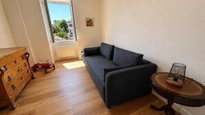 Una sala de estar con un sofá, un aparador de madera y una mesita con un objeto decorativo.