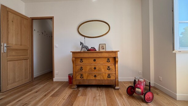 Una habitación con un aparador de madera, un espejo, un caballito de juguete y un coche de juguete.