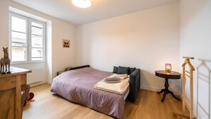 Une chambre à coucher avec un lit, un bureau en bois, une petite table et une fenêtre.