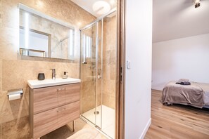 A modern bathroom with a glass shower enclosure, a vanity with a mirror, and a wooden floor. - “Chambre Mésange” – Lake View, Private Terrace & Wi-Fi (Excenevex)