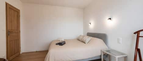 Ein schlichter Schlafzimmer mit Bett, Nachttisch und Holztür.