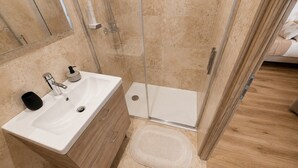 Un baño con lavamanos, espejo y ducha.
