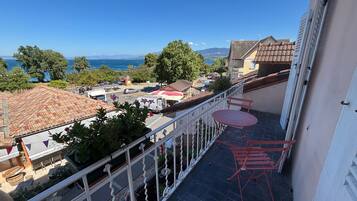 A balcony with a view of a town, a table, and chairs.