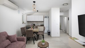 Eine moderne Wohnung mit Essbereich, Küchenzeile, Wohnzimmer und Fernseher.