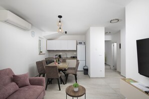 A modern apartment with a dining area, kitchen, living room, and a TV. - Family Villa Korina in Peroj (Peroj)
