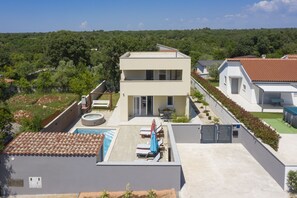 Ein modernes, zweistöckiges Haus mit Pool auf dem Dach, einer überdachten Terrasse und einem Garten.