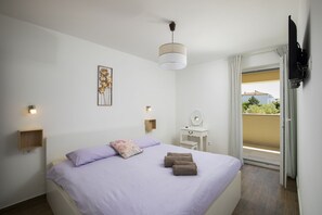 Ein Schlafzimmer mit Bett, Nachttisch, Spiegel und Blick ins Freie.