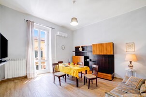 Una sala de estar moderna con comedor, un televisor de pantalla plana, un sofá y una lámpara.