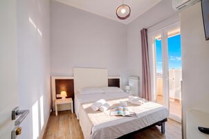 Habitación de hotel con cama, mesita de noche, lámpara y vistas al cielo a través de la ventana.