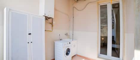 Una sala de lavandería con lavadora, secadora y calentador de agua.