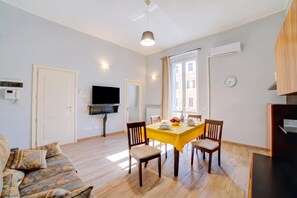 Una sala moderna con comedor, un televisor de pantalla plana y un ventanal grande.