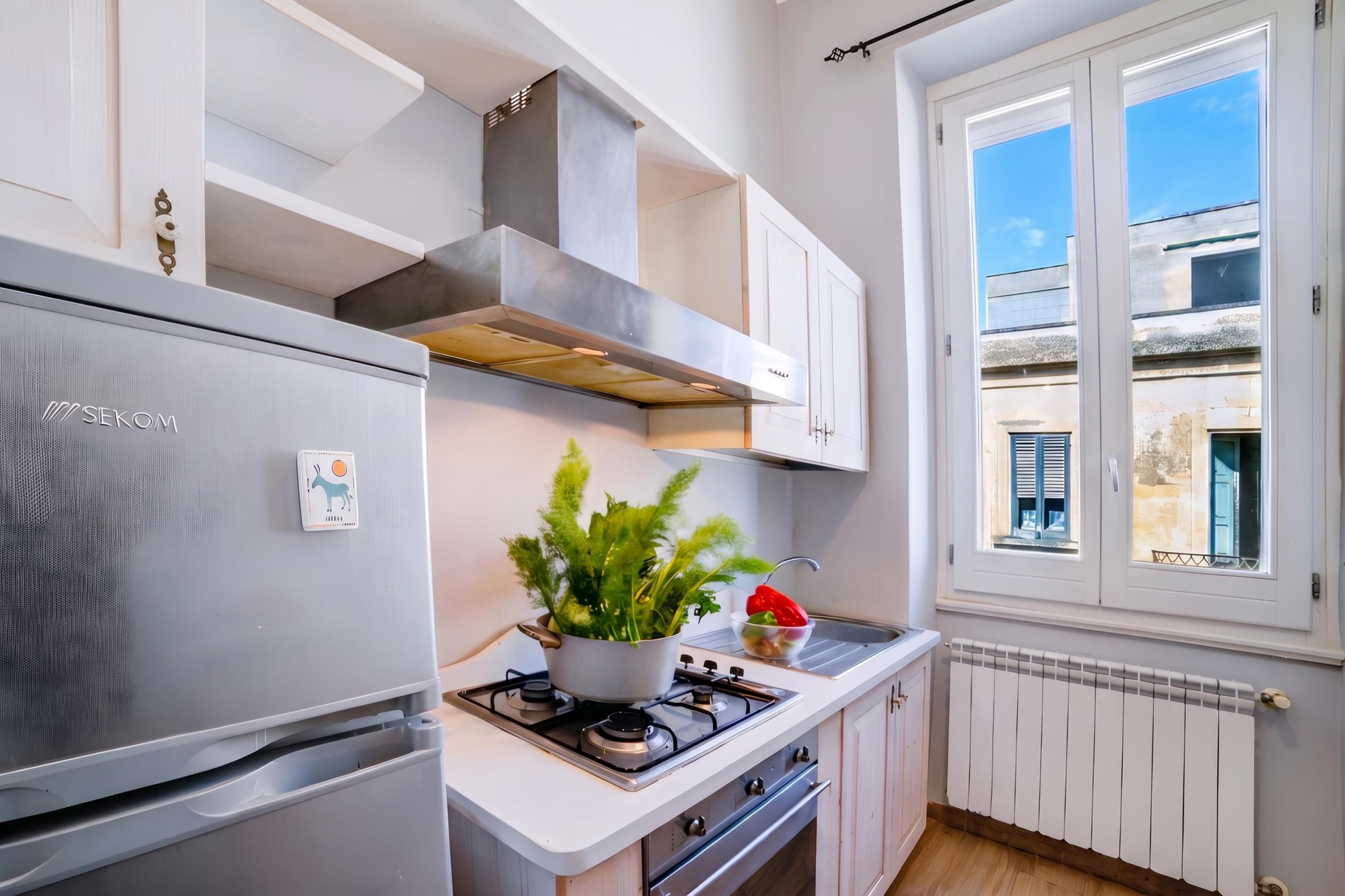 A modern kitchen with a built-in gas stove, stainless steel refrigerator, and white cabinetry.