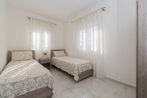 Un dormitorio con dos camas, una mesita de noche y una ventana con cortinas.