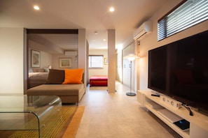 A modern living room with a sofa, a glass coffee table, a flat-screen TV, and a floor lamp.