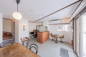 Et moderne køkken med en central ø, et spiseområde med et træbord og stole, samt udsigt gennem en glasdør.