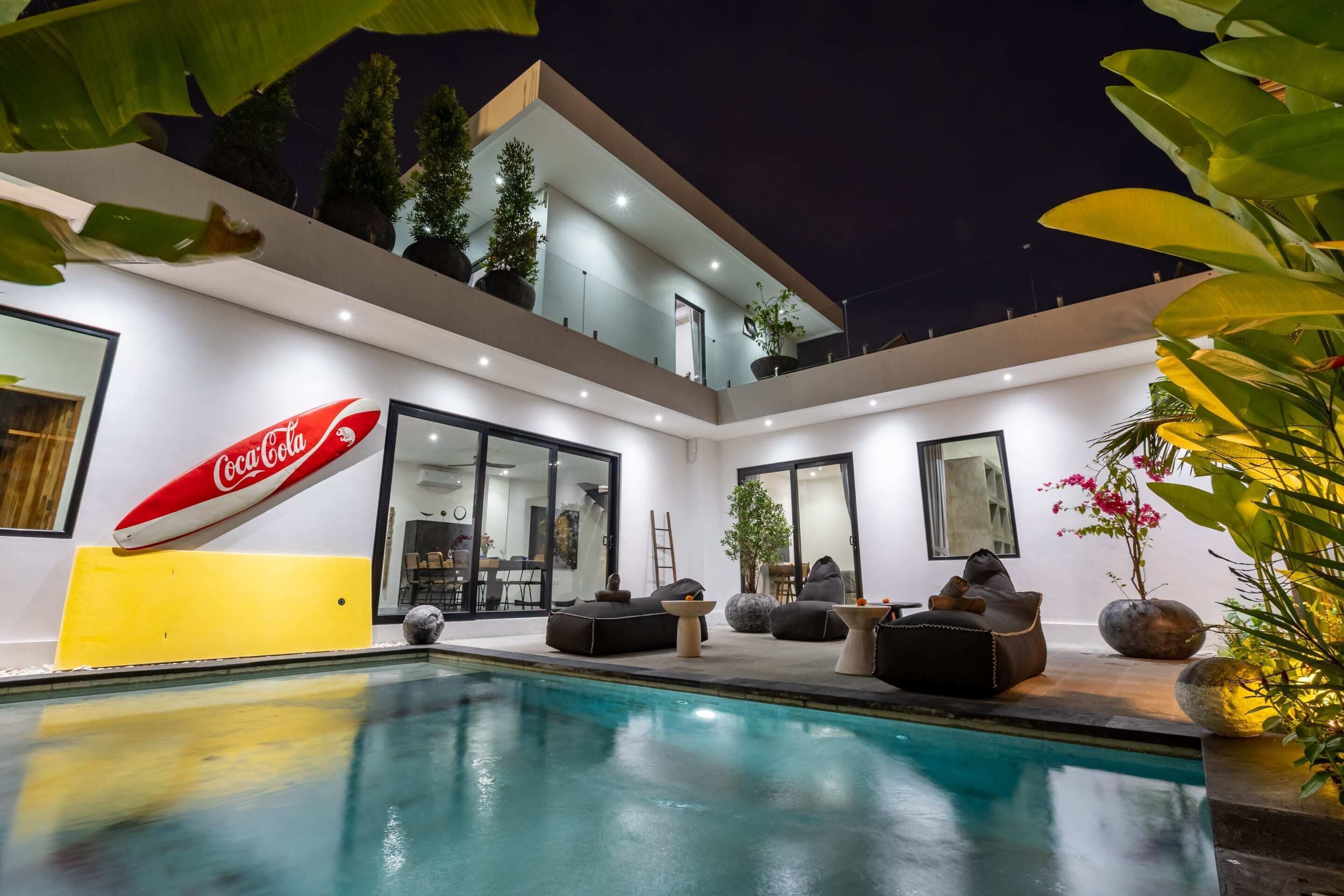 A modern house with a swimming pool, outdoor seating, and a Coca-Cola sign.