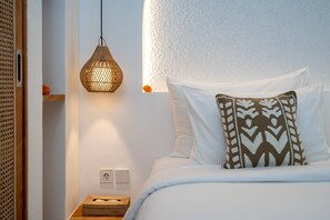 Ein Schlafzimmer mit einem Bett, einer Hängelampe, einem Nachttisch mit Korb und einer Steckdose.