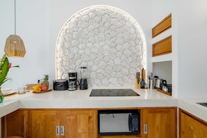Eine moderne Küche mit Steinrückwand, Holzschränken, einer eingebauten Mikrowelle und verschiedenen Küchengeräten.