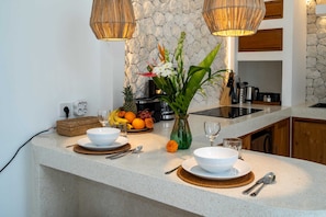 Eine Küchenarbeitsplatte mit Steinrückwand, eine Obstschale, eine Vase mit Blumen und eine Kaffeemaschine.