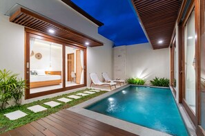 Ein moderner Poolbereich im Freien mit Holzterrasse, Liegestühlen und einem gläsernen Schlafzimmer.