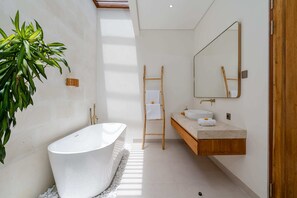 A modern bathroom with a freestanding bathtub, a wooden ladder, a large mirror, and a plant. - Villa Arunika by Elysian (Kerobokan)