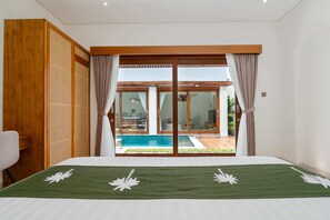 Ein Schlafzimmer mit einem großen Bett, Blick auf einen Swimmingpool und einer Holzwand.